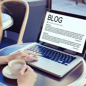 Frau mit Laptop und Kaffee liest Blogbeitrag im Café
