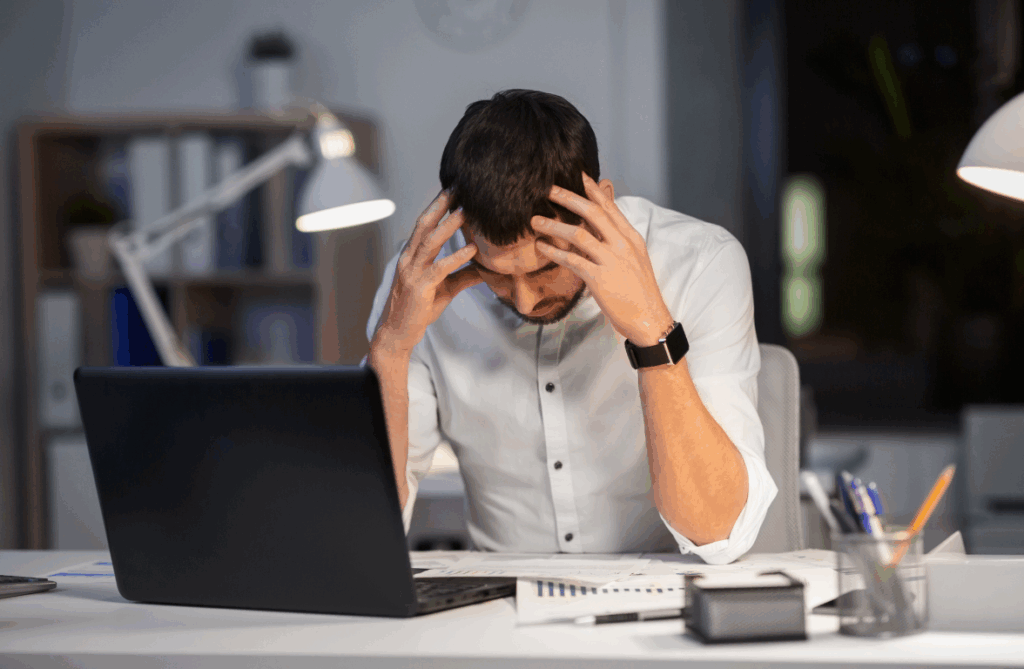 Selbstständiger Mann am Schreibtisch mit Frust über ausbleibende Kunden – Symbolbild für falsche Preisgestaltung im Coaching-Business
