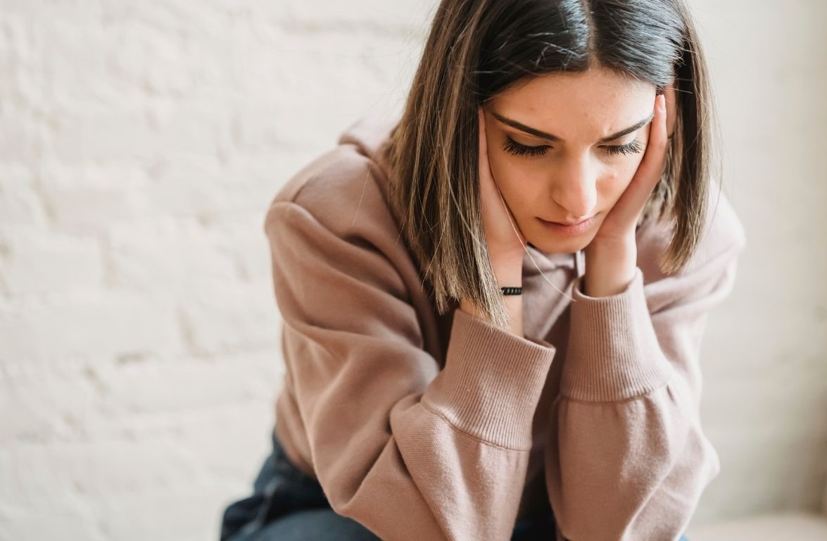 Frau mit Sorgenmiene hält den Kopf in den Händen – symbolisiert Selbstzweifel im Business